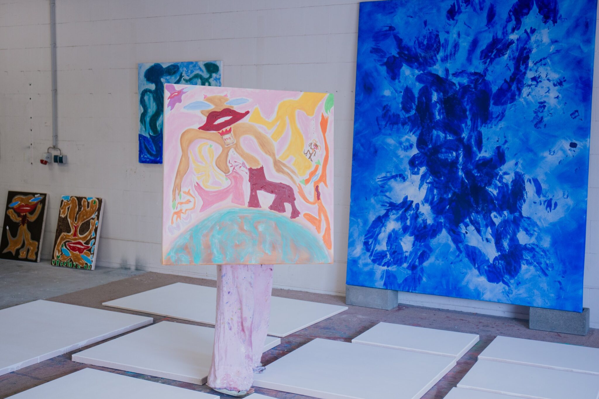 Franziska Katharina Röhrs hinter einem ihrer Gemälde im Atelier, umgeben von Leinwänden
